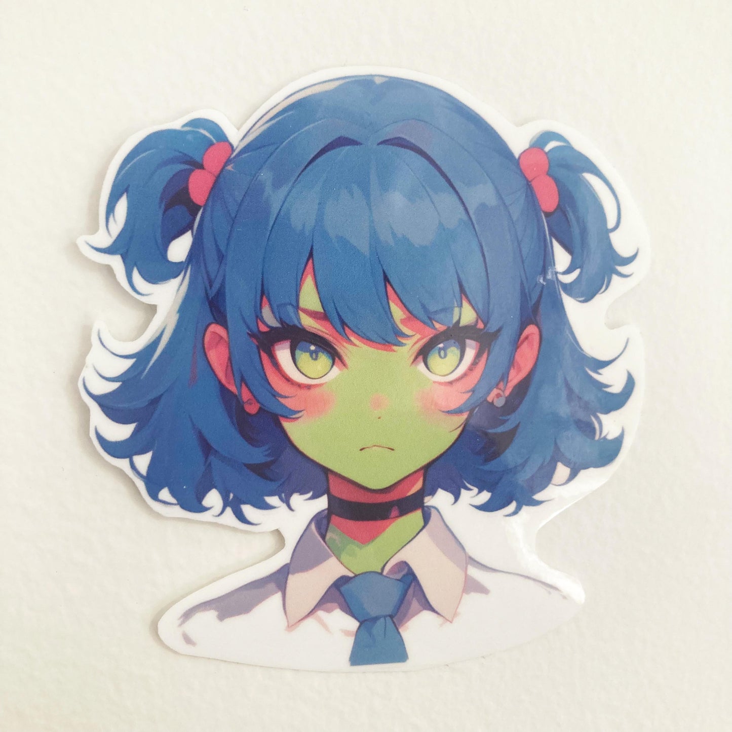 Sticker of an anime-style character with blue twin-tails, pink hair ties, green skin, and yellow eyes. The character wears a white shirt, blue tie, and black choker, set against a plain background.