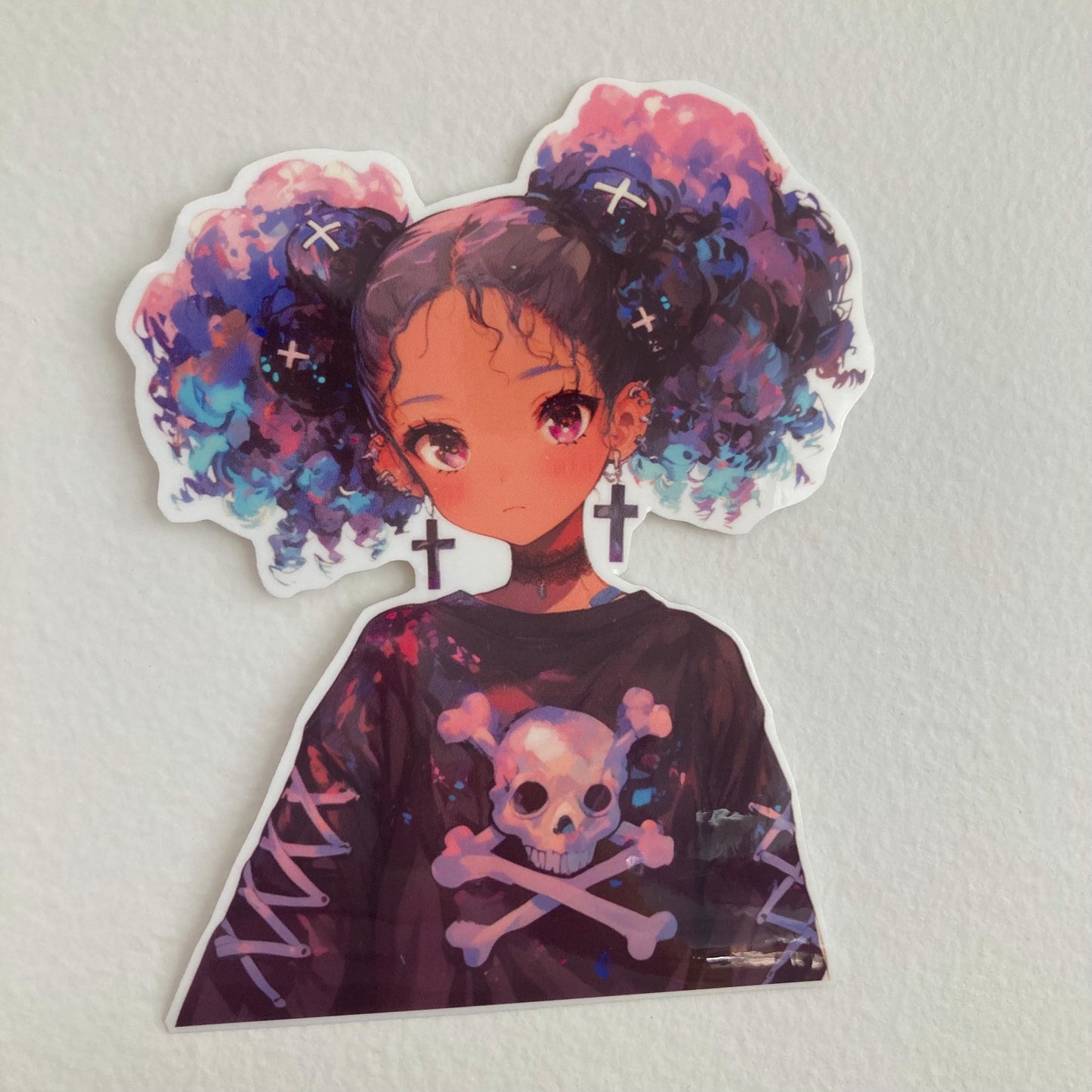 A sticker of an anime-style character with purple and blue curly hair, cross earrings, and a black shirt featuring a skull and crossbones, placed on a plain white surface.