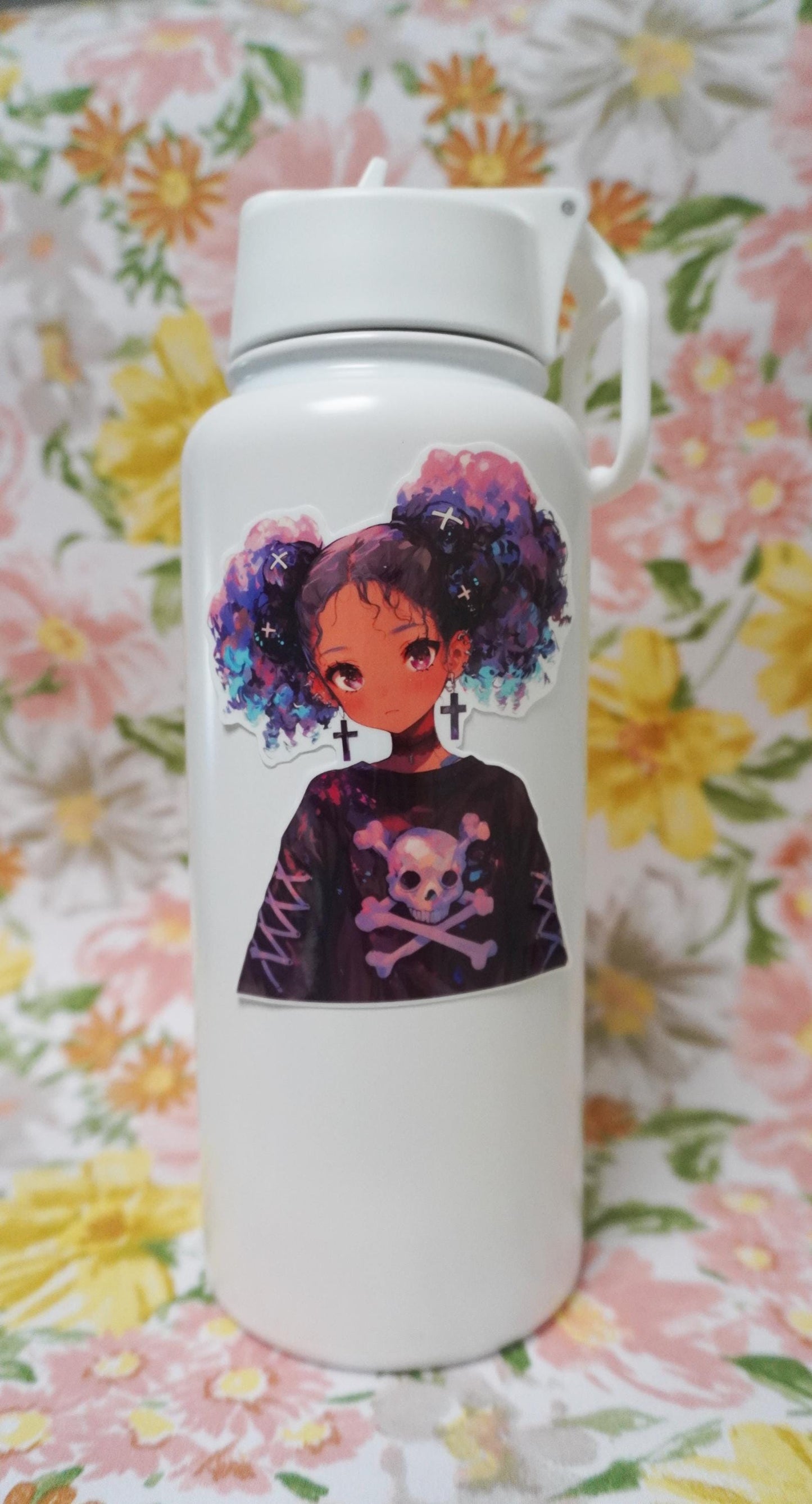 A white water bottle with a sticker of an anime-style character with purple and blue curly hair, cross earrings, and a skull-themed shirt, set against a floral-patterned background in soft pastel colors.