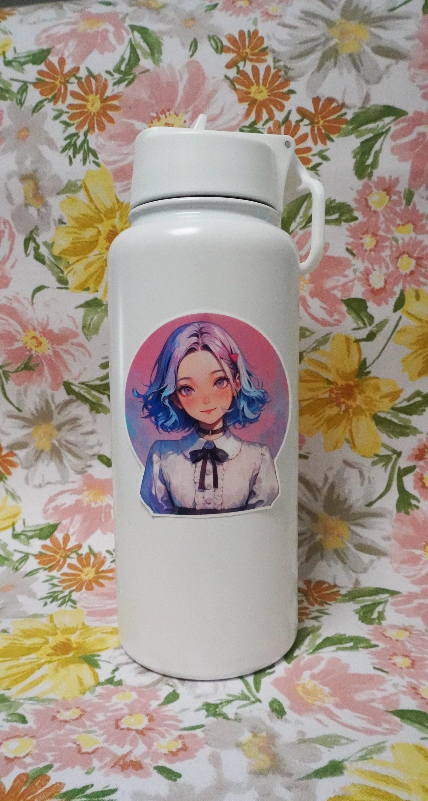 A white bottle decorated with a round anime-style sticker of a smiling character with short blue and pink hair, wearing a white blouse with a black bow. The background is pink, and the bottle is set against a floral-patterned backdrop.