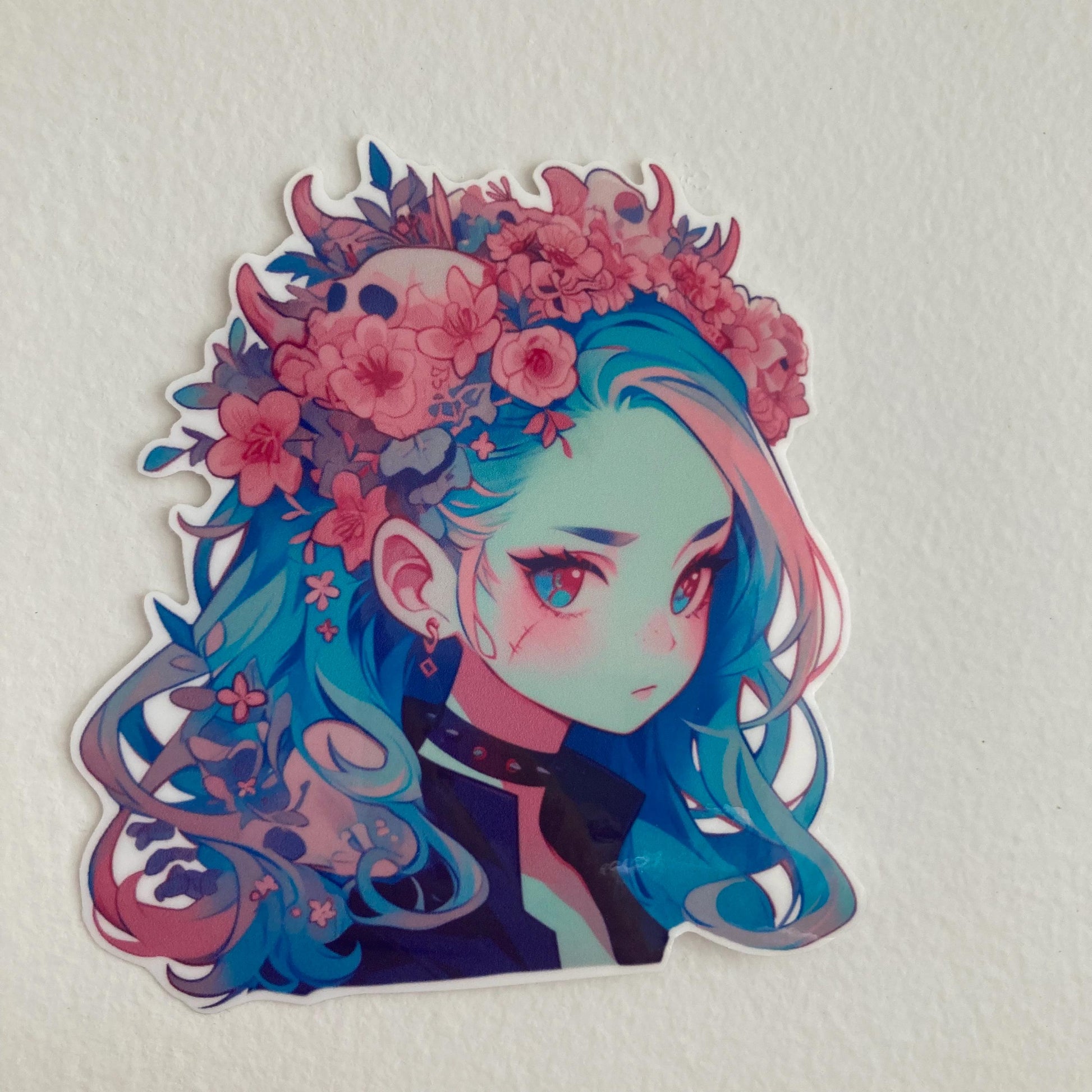 A sticker of a girl with blue hair, a floral crown, and a black choker, placed against a plain light-colored background.