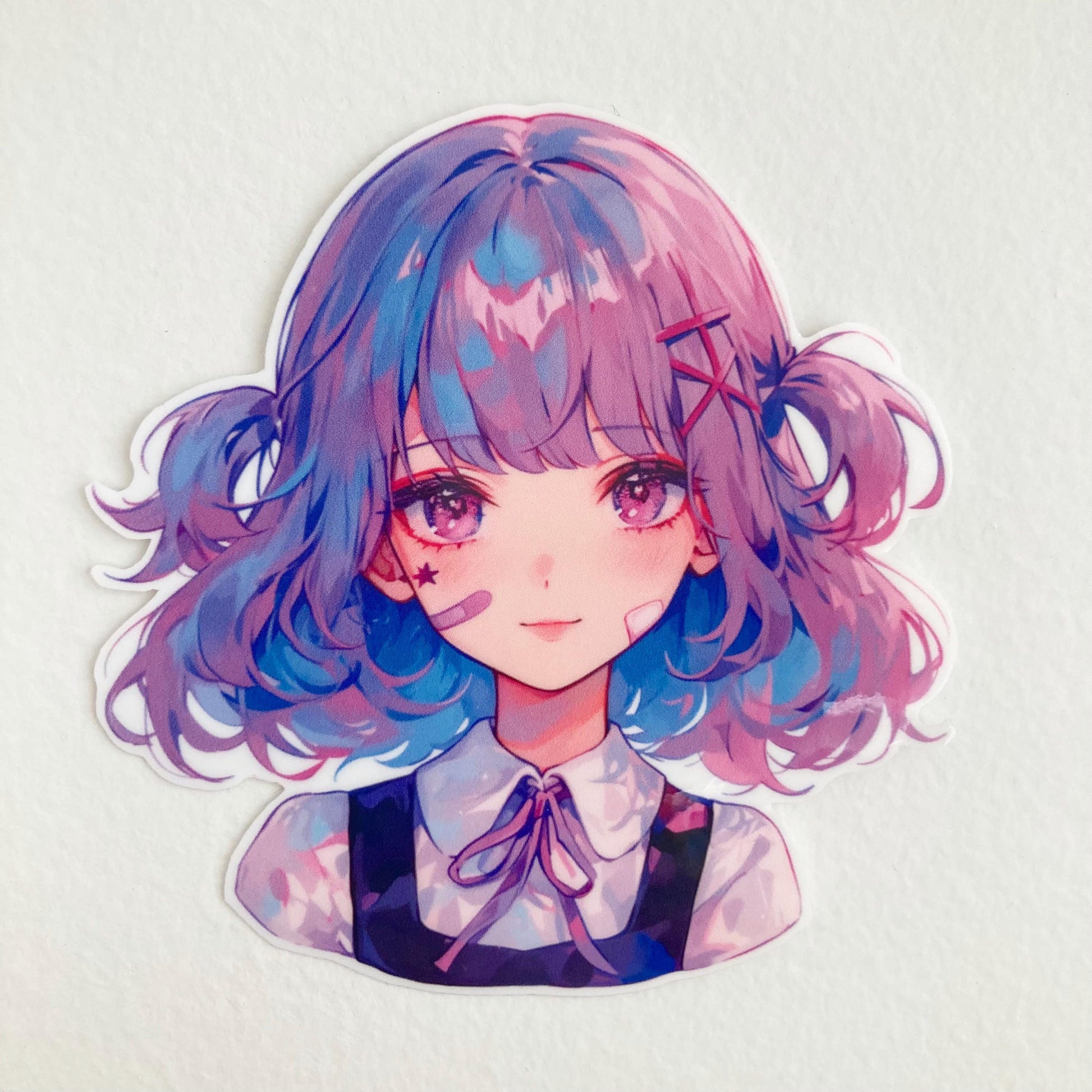 A sticker of an illustrated girl with short wavy hair in shades of blue and pink. She has pink eyes, star and bandage markings on her face, and wears a collared blouse with a bow and a dark sleeveless dress. The background is plain white.