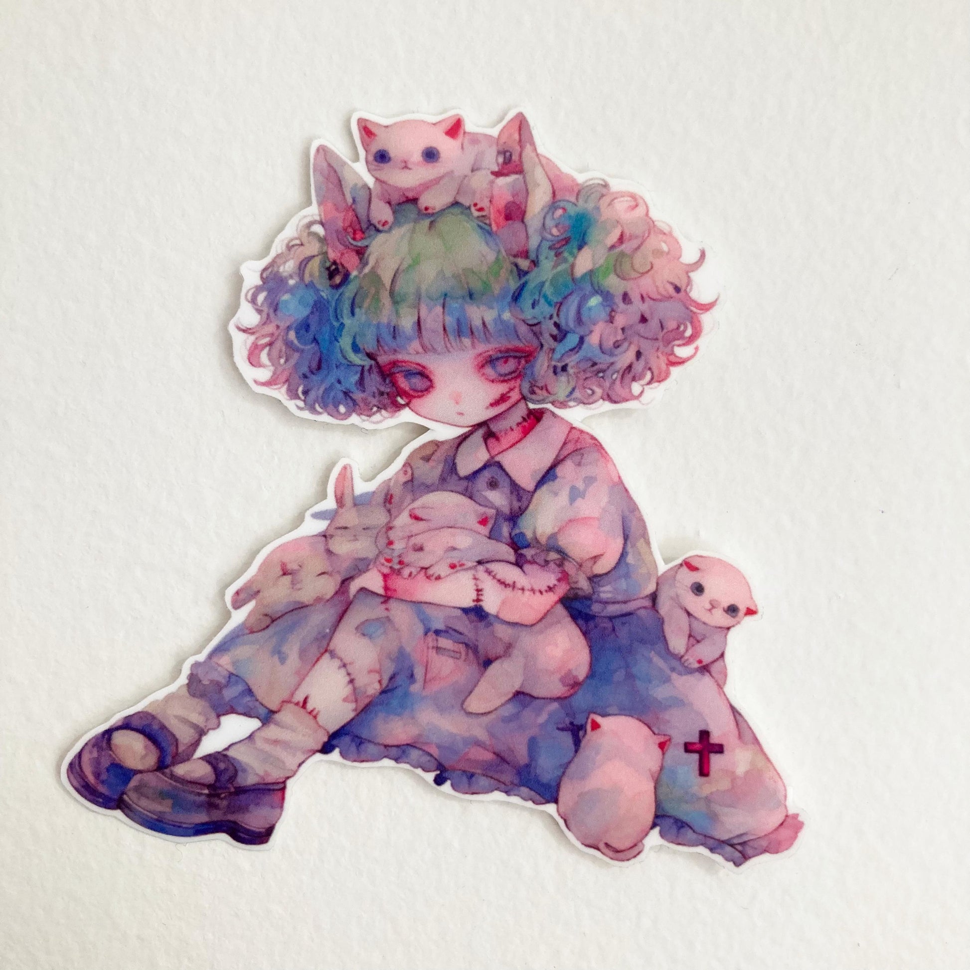 Sticker of an anime-style character with pastel curly hair, sitting with white cats and bunnies. The character wears a blue dress with stitched limbs and holds a animals. A red cross is visible on their dress. Set against a plain background.